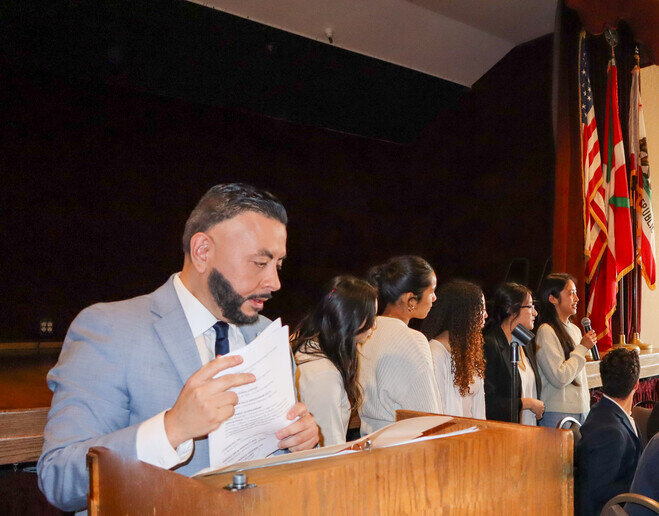 a man in a suit reading a paper at a podium