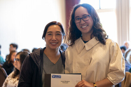 a woman holding a paper with a woman smiling