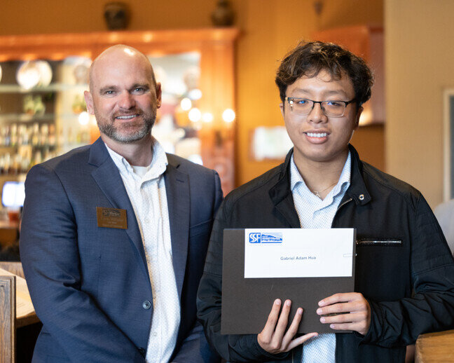 a man holding a folder with a person standing next to him