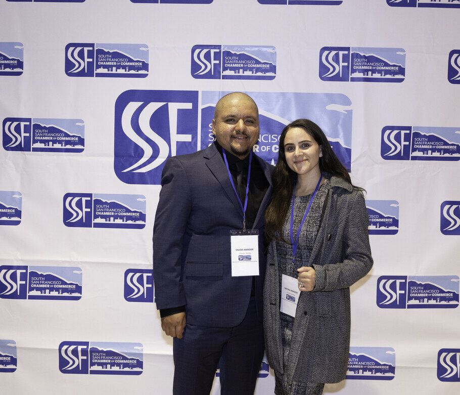 a man and woman standing in front of a wall with logos