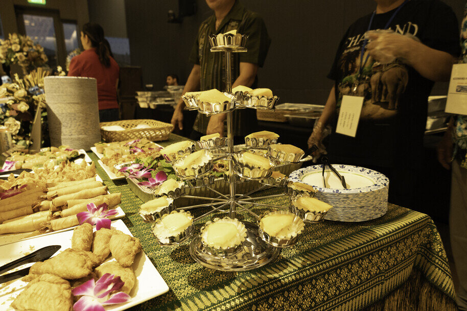 a group of people standing around a table with food