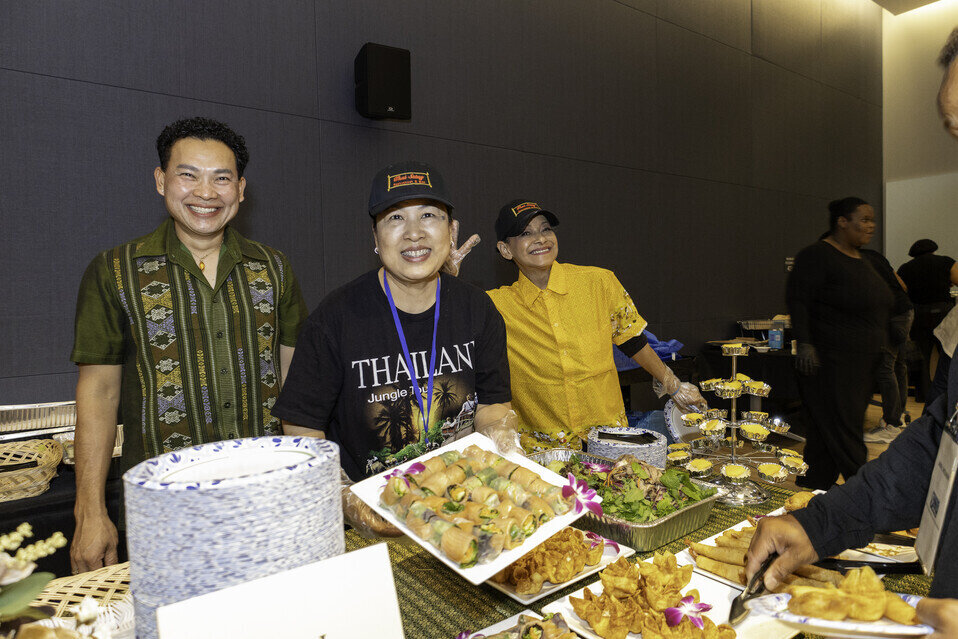 a group of people standing next to a table full of food