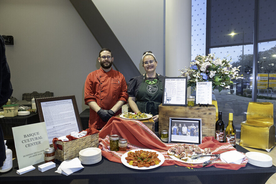 a couple of people standing next to a table with food