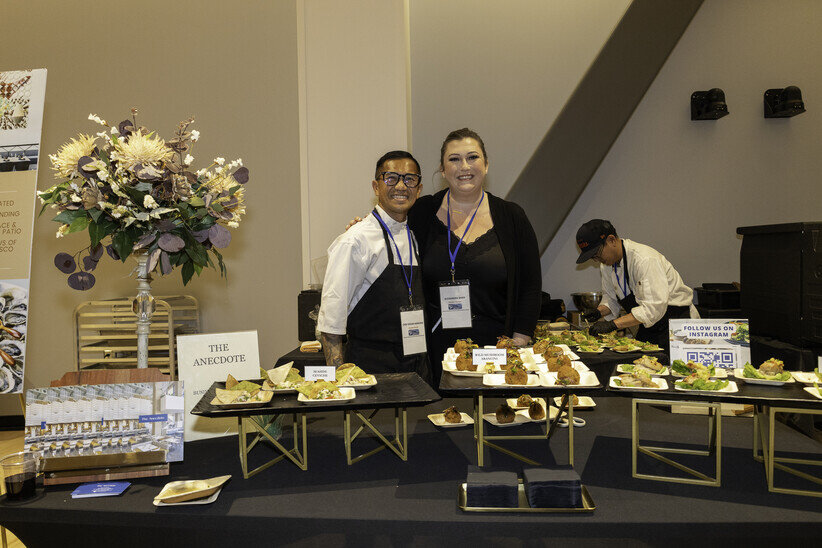 a couple of people standing behind a table of food