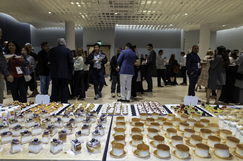 a group of people standing around a table with desserts