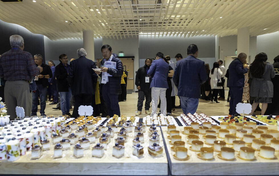a group of people standing around a table with desserts