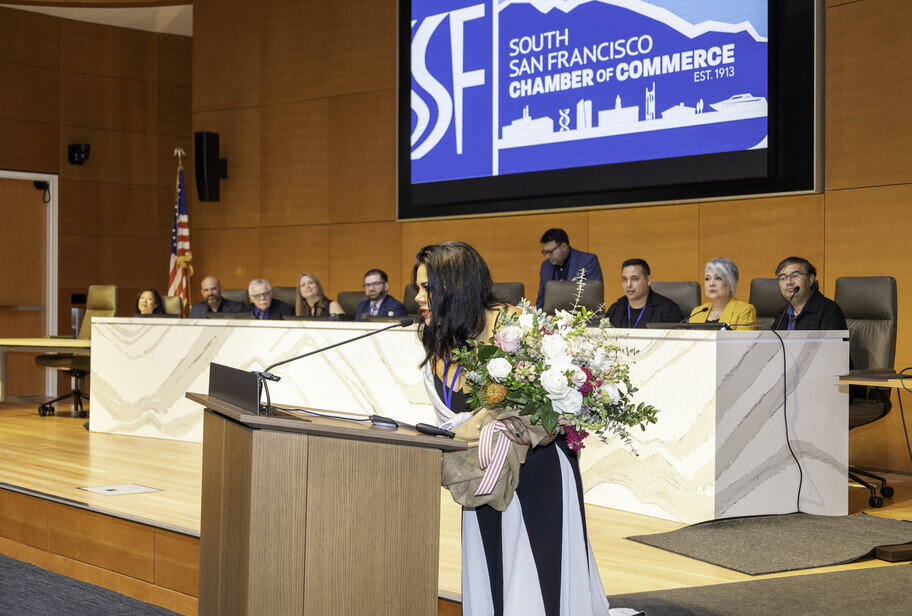 a woman standing at a podium with a bouquet of flowers