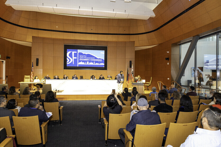 a group of people sitting in chairs in a room with a screen