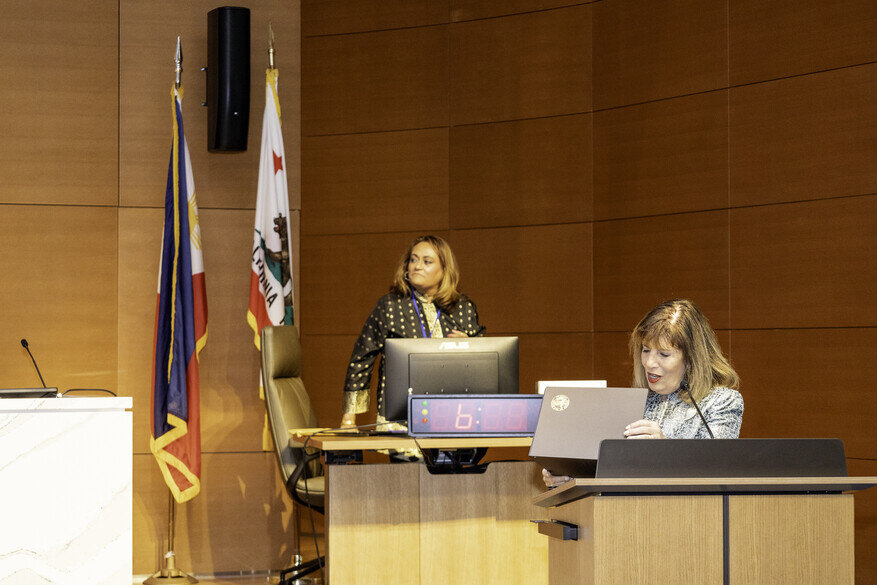 a woman sitting at a podium with a laptop